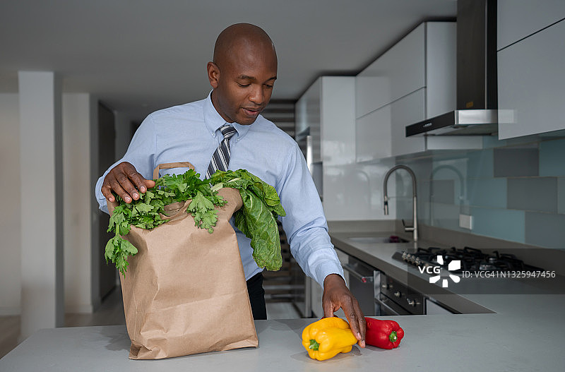 商务男人下班后带着一袋杂货回家图片素材