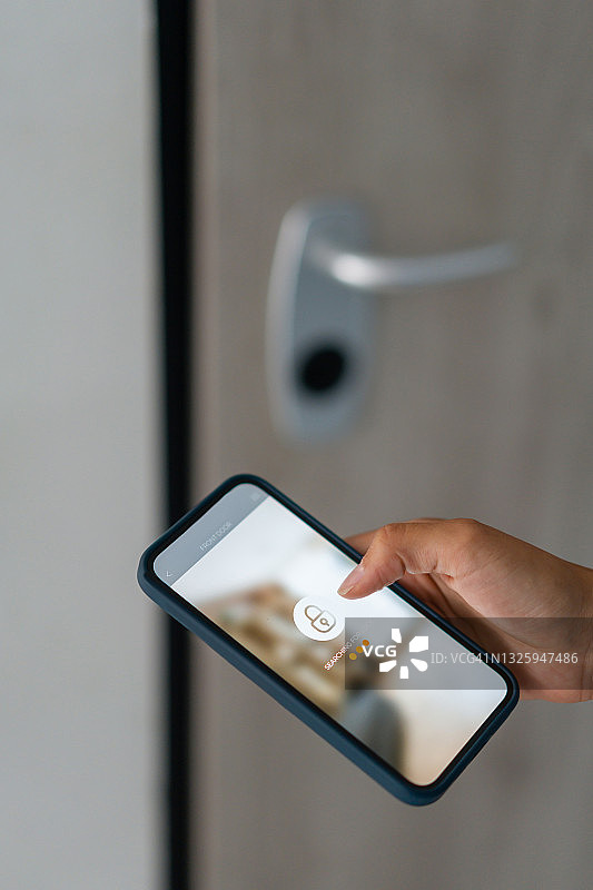 女人用手机App锁门图片素材