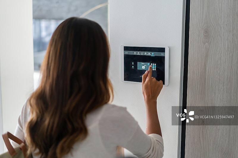 使用家庭自动化系统锁门的女人图片素材