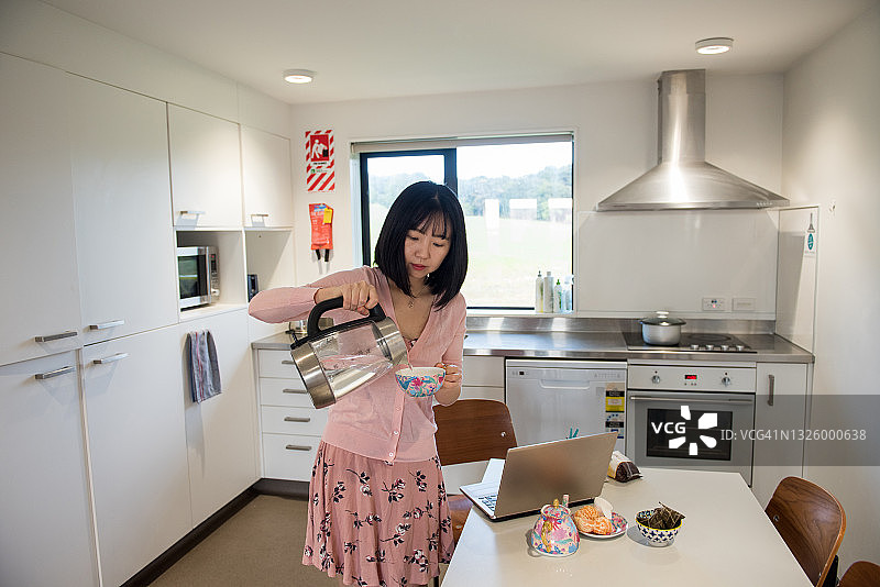 年轻的亚洲女人在简易厨房准备早餐图片素材