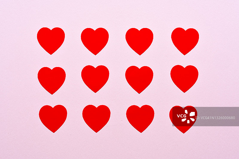 粉色背景上排列好的红色心形贴纸图片素材