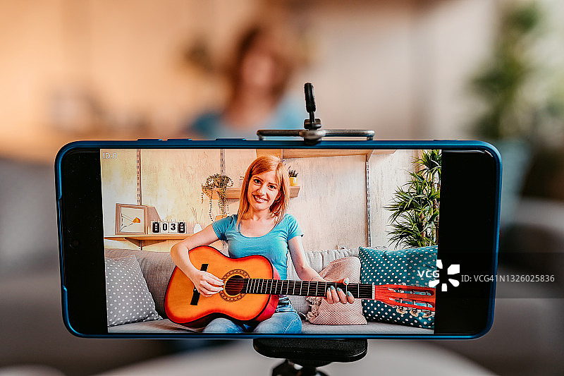 用手机制作吉他演奏教程的女人图片素材
