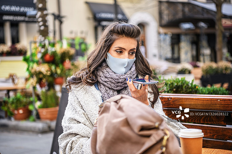 戴口罩的女人餐厅喝咖啡玩手机图片素材
