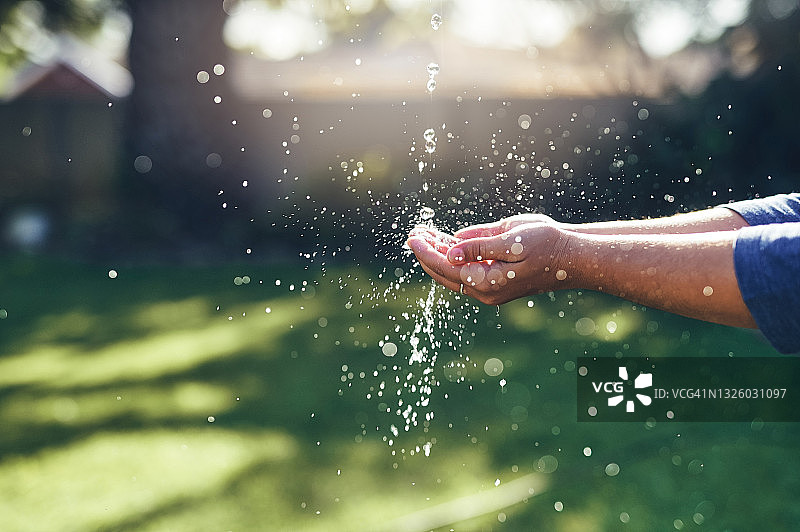 一个不认识的女人独自站在她的花园里，伸出手去接水图片素材