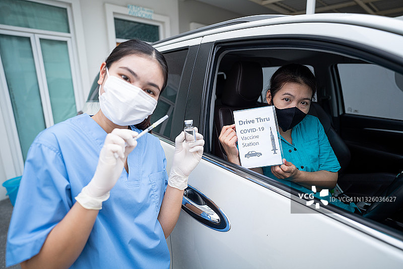 驾车接种疫苗点，亚洲年轻医生为驾车人士注射新冠疫苗图片素材