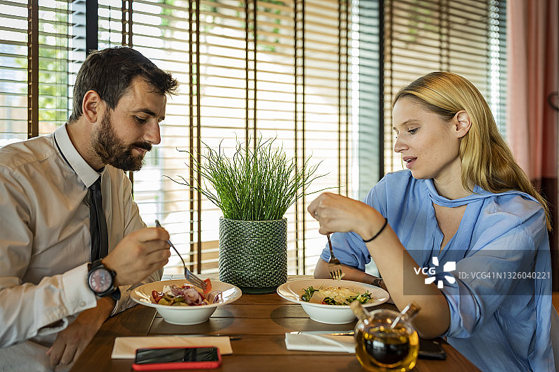 年轻女人和英俊的男友在现代餐厅里享受浪漫的晚餐图片素材