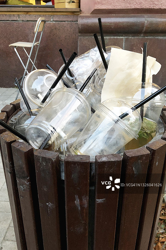垃圾桶里的塑料咖啡杯和吸管图片素材