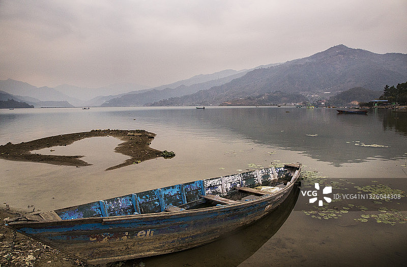 尼泊尔博克拉费瓦湖的静谧日出，蓝色独木舟倒影图片素材