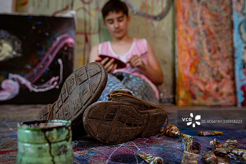 倚靠在墙上，专注的青少年艺术家正在调色图片素材