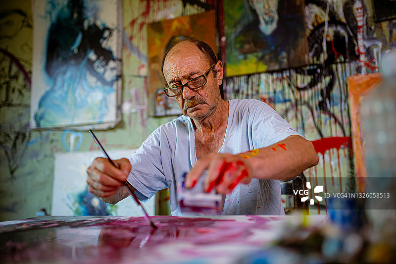 年长的艺术家直接在画布上倒颜料图片素材