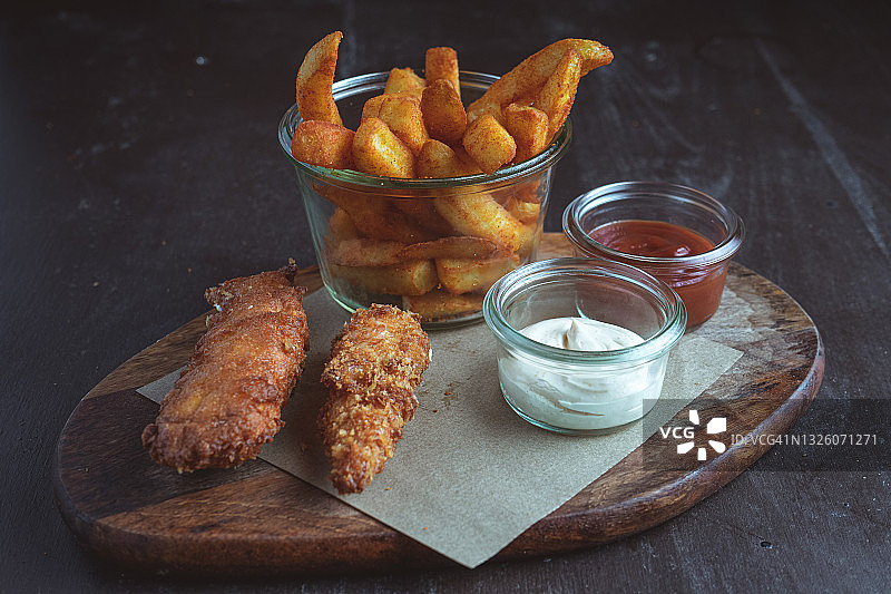 木板上的两块炸鸡柳和炸薯条图片素材