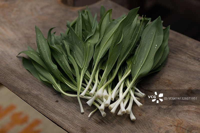 木质背景上的新鲜野生蒜苗与水滴图片素材