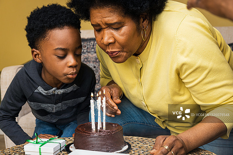 奶奶和孙子在家吹生日蛋糕蜡烛图片素材