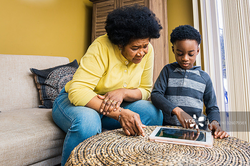 男孩和奶奶在家里的客厅里使用平板电脑图片素材