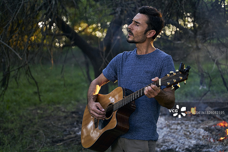 日落时弹吉他的年轻音乐家肖像照图片素材