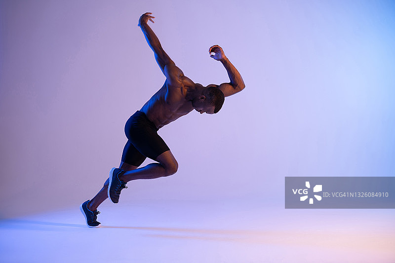 活跃的黑人男性运动员在摄影棚内跑步图片素材
