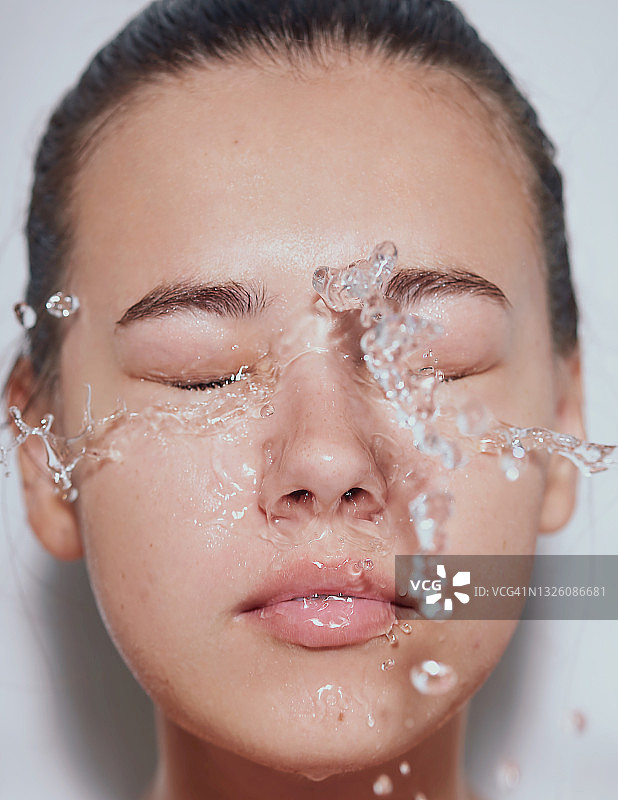 年轻漂亮的女子，肌肤干净清爽，水花飞溅——白色背景图片素材