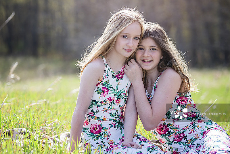 两位穿着夏装的年轻女孩坐在户外的毯子上图片素材