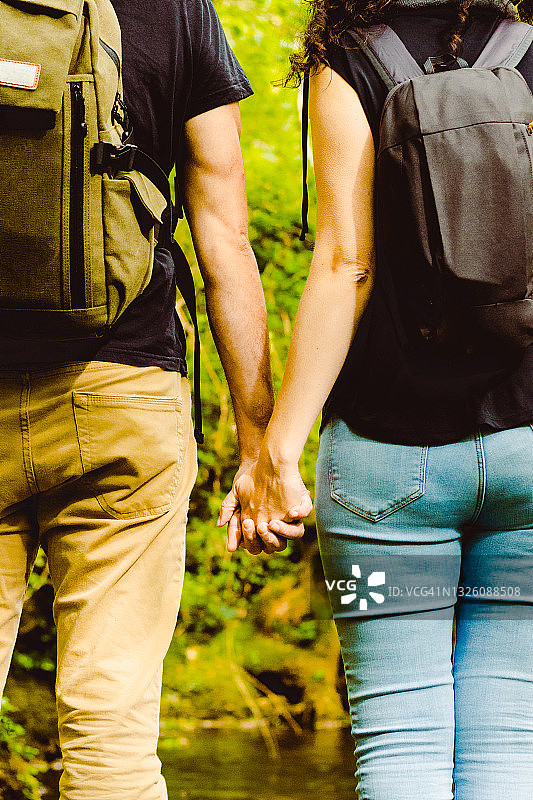 情侣在森林里手牵手背包旅行图片素材