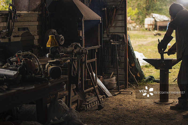 铁匠用大锤在铁砧上加工一块钢材图片素材