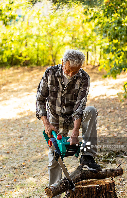 年长的男子正在砍伐倒下的树木图片素材