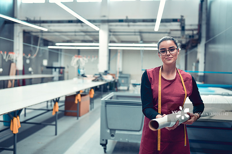 微笑的女纺织工人在设置印花辊筒机图片素材