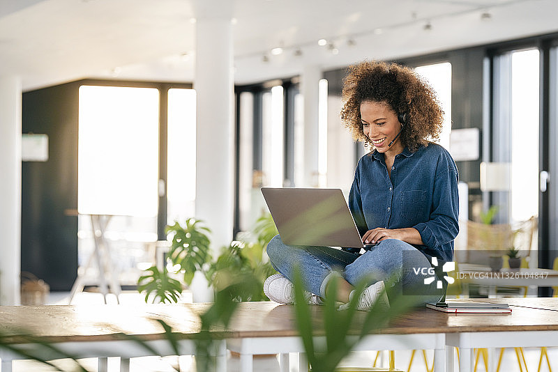 微笑的女客服代表在办公室咖啡厅使用笔记本电脑工作图片素材