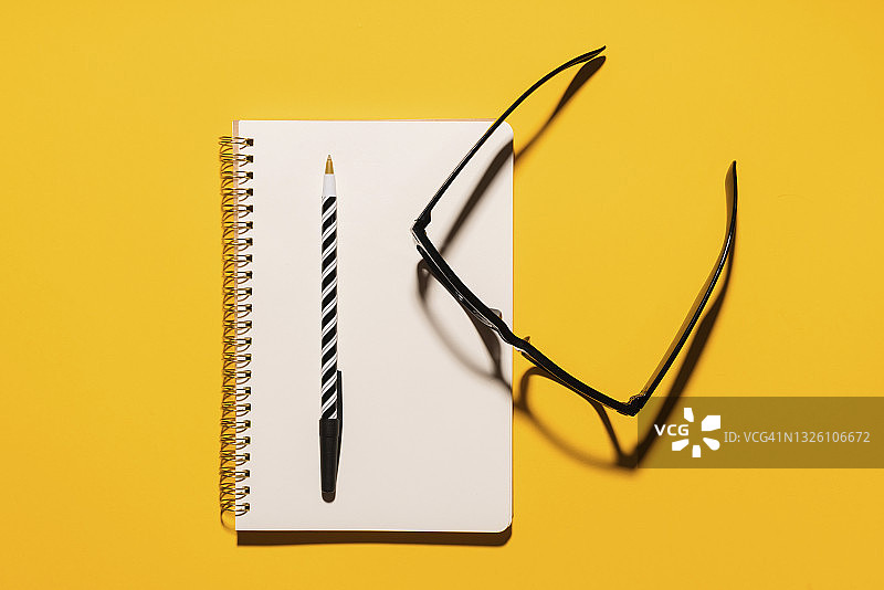 眼镜、笔和再生纸笔记本的影棚照片图片素材