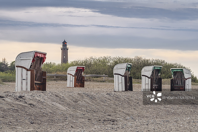 黄昏时分空旷海滩上的带罩沙滩椅，背景是诺伊兰灯塔图片素材