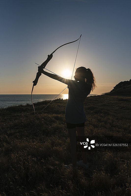 日落时分，手持弓箭的年轻女人图片素材