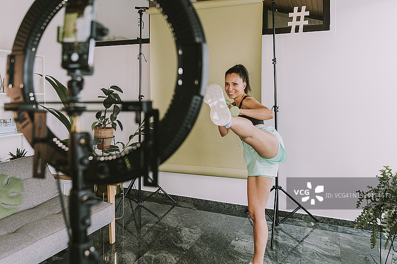 女健身教练在家录制踢腿视频图片素材