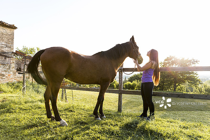女子站在栅栏旁，手持马具图片素材