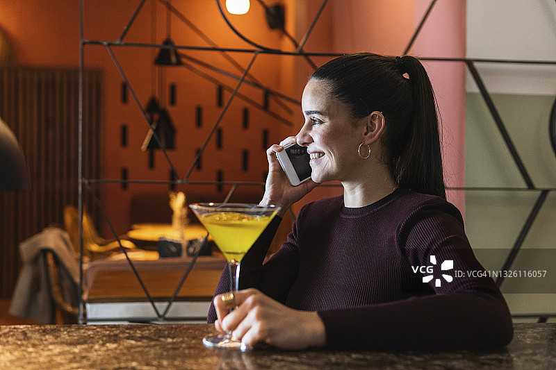 年轻女人在餐厅里一边微笑一边用手机聊天图片素材
