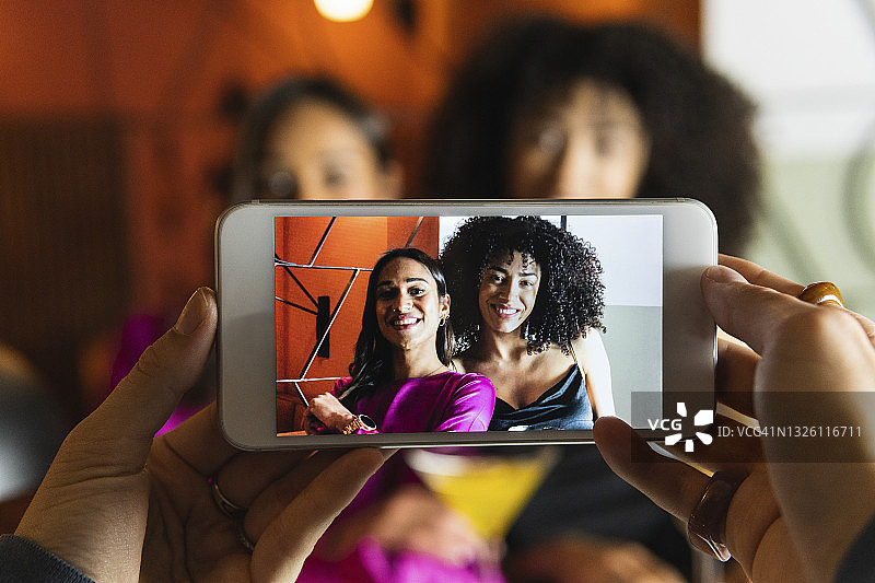 女人在餐厅用智能手机拍摄朋友图片素材