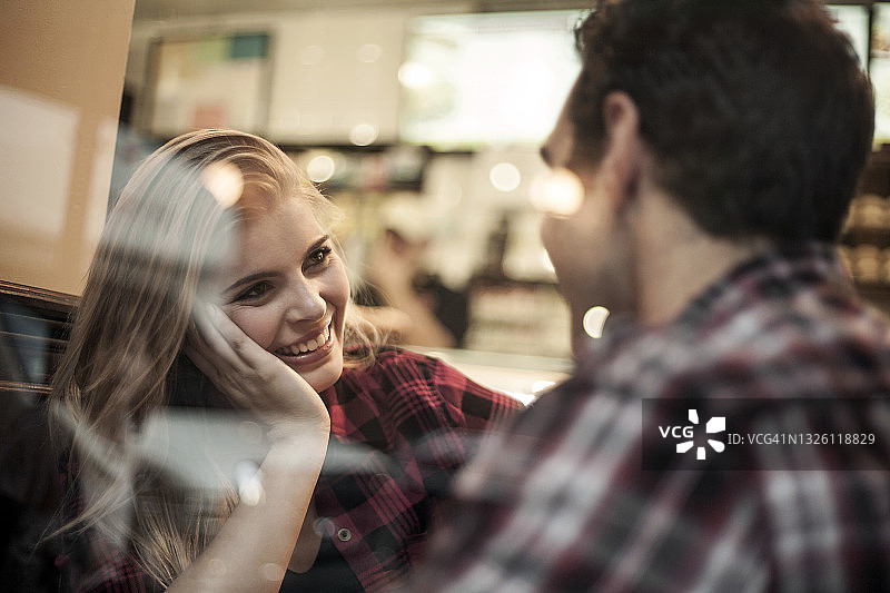 透过咖啡馆的窗户看微笑的女人和她的男朋友图片素材