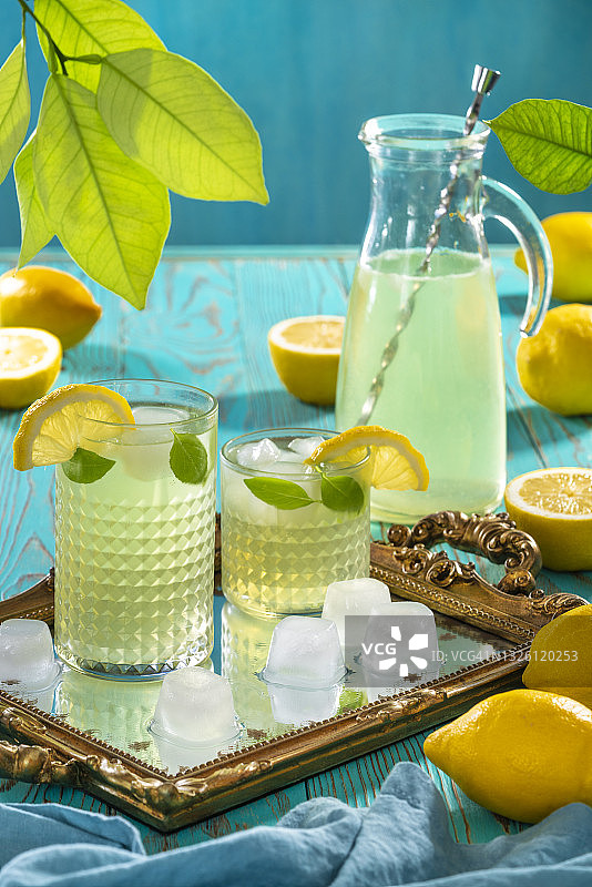 两杯柠檬水和冰块在绿松石背景上，清爽夏日图片素材