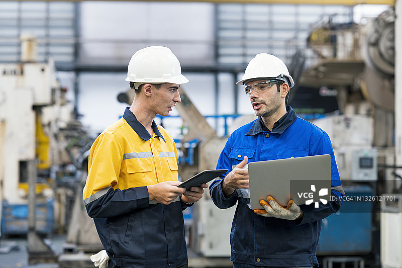 生产计划控制工程师在生产线前讨论或开会，跟进生产计划、原材料和底盘零件的质量控制。汽车工业中的汽车零件生产。图片素材