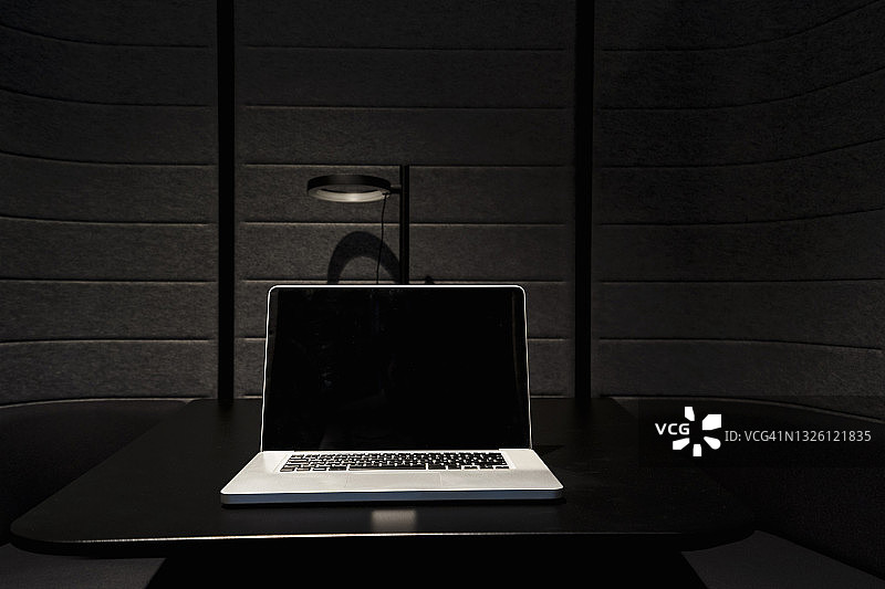 办公室黑色桌面上放置的笔记本电脑图片素材
