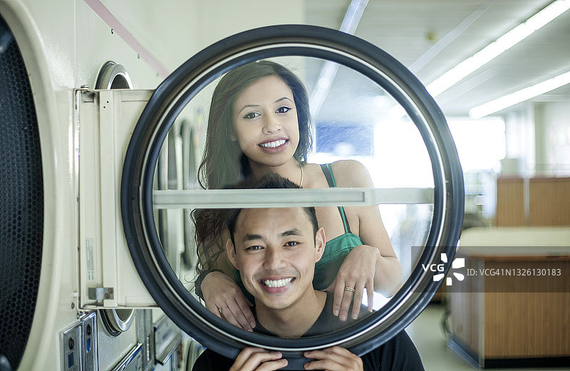 微笑的男人和女人在自助洗衣店玩得开心图片素材