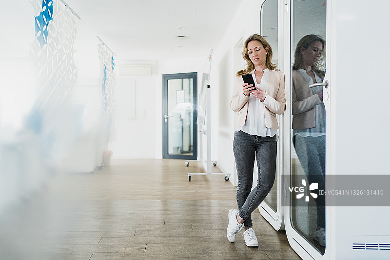 在办公室用手机发短信的女商人图片素材