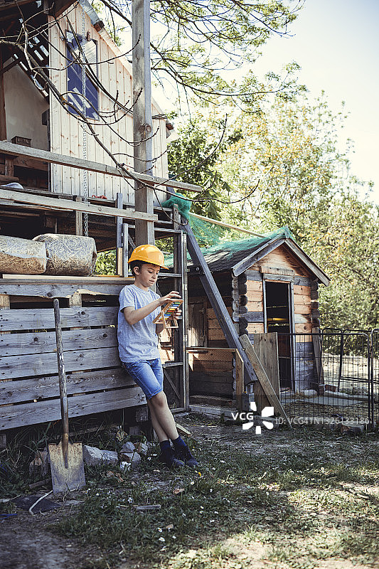 戴黄色安全帽的男孩在后院玩玩具图片素材