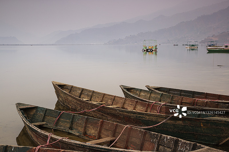 尼泊尔博克拉费瓦湖上古老独木舟的宁静日出倒影图片素材