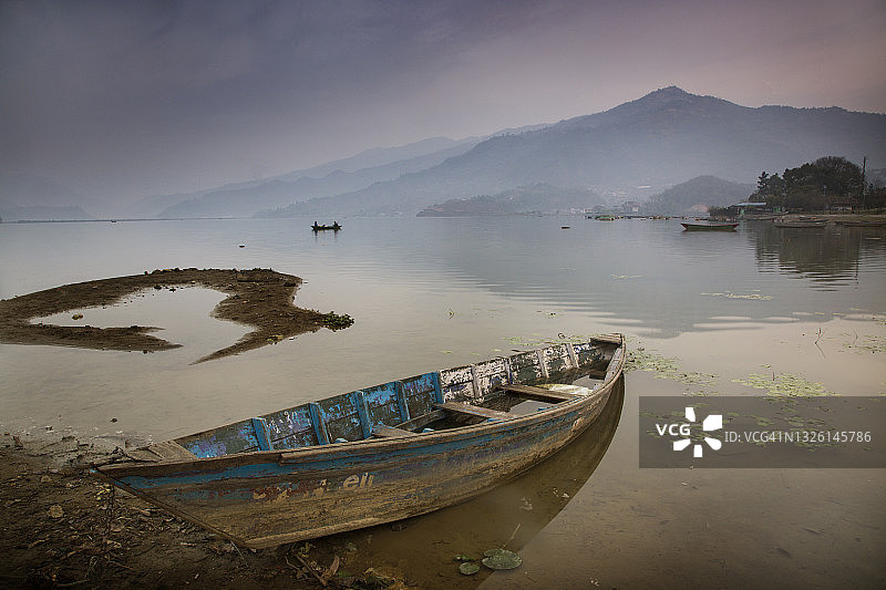 尼泊尔博克拉费瓦湖的静谧日出，蓝色独木舟倒影图片素材
