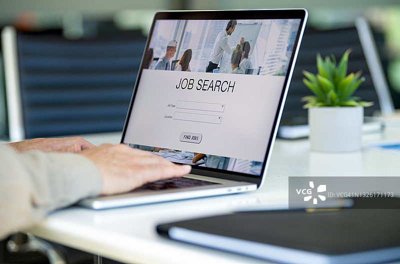 年长的商人看着笔记本电脑上的求职网站图片素材