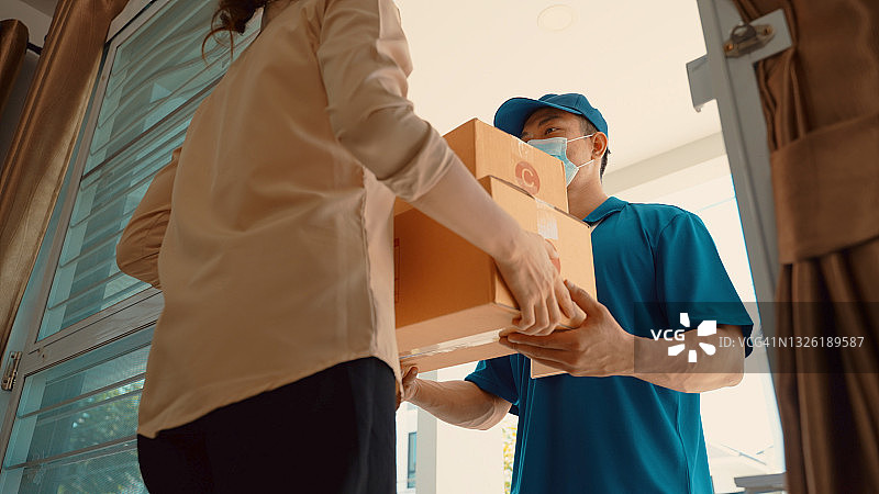 疫情期间，亚洲快递员送货上门，佩戴口罩手套图片素材