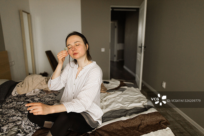 年轻女子在家做面部刮痧按摩肖像图片素材