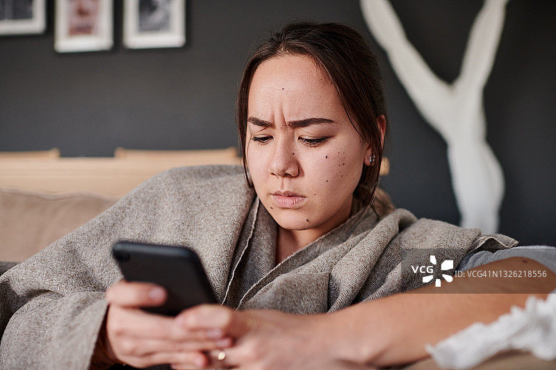 女人在家中使用手机时表情严肃的照片图片素材