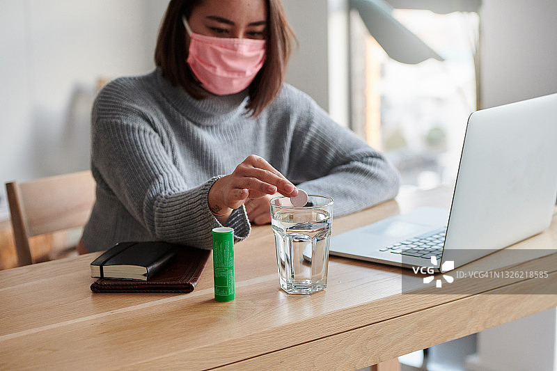 在家工作时，女子将泡腾片扔进一杯水中图片素材