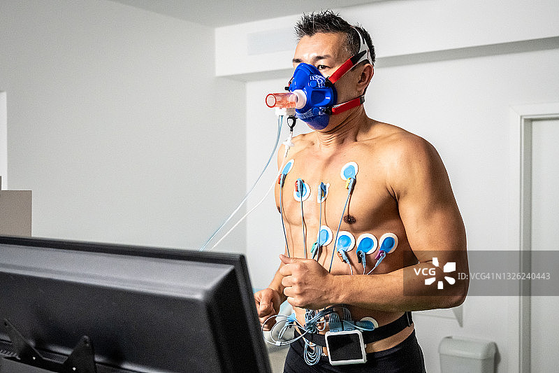 在心肺压力测试期间，在跑步机测力计上跑步的男人图片素材