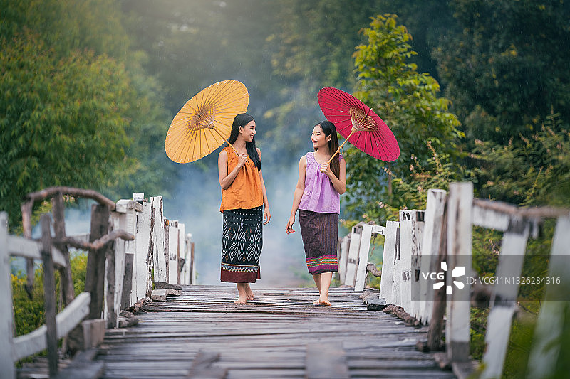 两个女人雨中撑伞在桥上回家图片素材